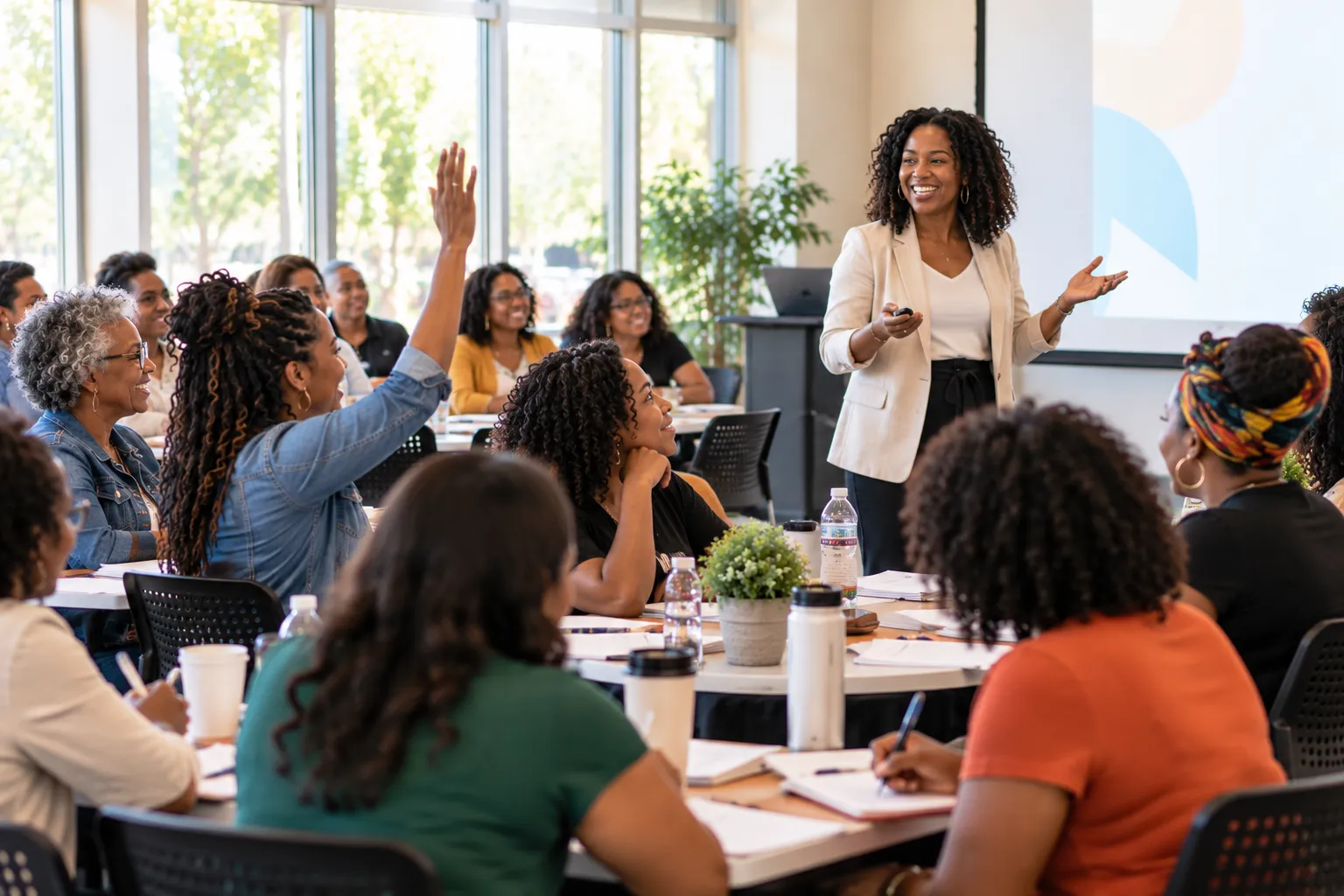 Women entrepreneurs engaged in a workshop, one raising her hand to ask a question